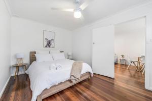 a white bedroom with a bed with two towels on it at Beach Shack No. 7 in Crescent Head