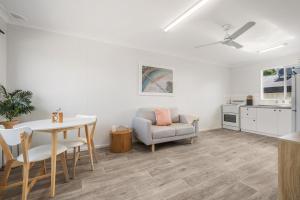 a white living room with a table and a chair at Beach Shack No. 6 in Crescent Head
