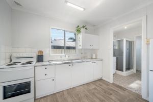 a white kitchen with a sink and a stove at Beach Shack No. 6 in Crescent Head +7 photos