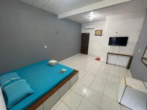 a room with a blue bed and a television at Hotel Torre Forte in Careiro