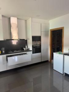Vila Nova da VeigaにあるVilla Machadoのキッチン(ステンレス製の電化製品、白いキャビネット付)