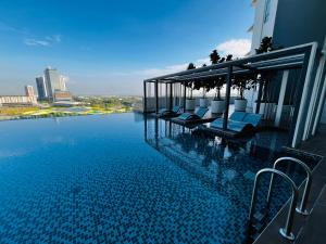 a swimming pool with lounge chairs on the side of a building at Dreamy Sunsuria Forum Homes-Setia City Mall, Setia City Convention Centre and National Institute of Health in Shah Alam