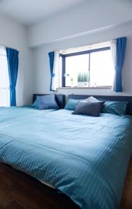 a bedroom with a large blue bed with a window at G63 駅徒歩3分 3人可能 名古屋駅から1駅 3-minute walk from the station in Nagoya