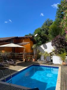 a swimming pool in a yard with chairs and a house at Pousada Parque da Mata in Paraty