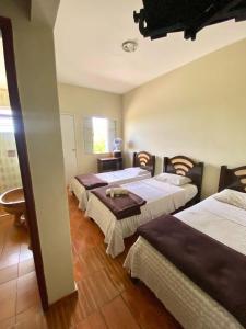 a group of three beds in a room at Hotel Rezende in Villa Nova de Resende +11 photos