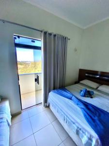 a bedroom with a bed and a large window at Hotel Rezende in Villa Nova de Resende