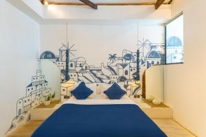 a bedroom with a blue bed with a mural on the wall at Santorini Suites Canggu in Canggu