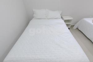 a white bed in a white room with a bed sidx sidx at Comfortable 1 Br In The Center Of Ciudad Del Este in Ciudad del Este