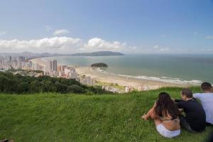 a group of people sitting on a hill overlooking a beach at Vista Azul Rooftop in São Vicente