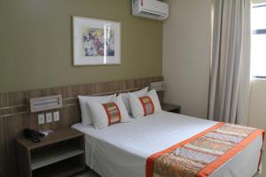 a bedroom with a bed with white sheets and pillows at Paiaguás Palace Hotel in Cuiabá