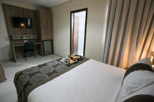 a hotel room with a bed with a tray of food on it at Paiaguás Palace Hotel in Cuiabá