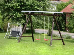 a swing set with two red swings in a yard at Apartment in Armsfeld mit Pool 