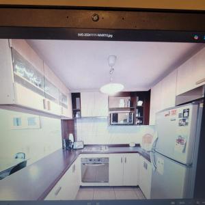 eine Küche mit weißen Schränken und einem weißen Kühlschrank in der Unterkunft Departamento vista al Mar, Costa Lilenes Concon in Valparaíso