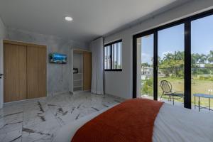 a bedroom with a bed and a tv on a wall at Perla 8- Exclusiva Moderna Villa 4 Habitaciones y Piscina in Sosúa