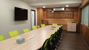 a conference room with a long table and green chairs at Hotel Damai in Parit Buntar