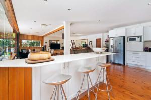 a kitchen with a white counter and stools at Cottage Point - Paradise Found in Berowra