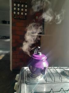 São Joaquim de BicasにあるSítio Eventos Nossa Senhora Aparecidaの煙の出るストーブの上の紫色のティーポット