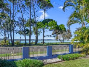 a blue fence with trees and the ocean in the background at Welcome to Bay Views on Esplanade in Tin Can Bay