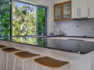 a kitchen with a counter with stools and a window at Welcome to Bay Views on Esplanade in Tin Can Bay