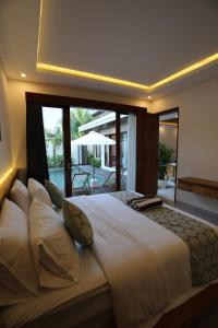 Un dormitorio con una gran cama blanca con una gran ventana. en Denaya Villa, en Ubud