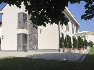 a white building with black shuttered windows and plants at Apartments Santis10 in Baška