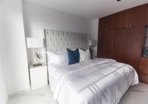 a white bedroom with a large bed with blue pillows at Modern 2BR Ocean view - Walk to Beach and Downtown in Puerto Vallarta +36 photos