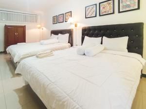 two beds in a room with white sheets and pillows at Gatsu Resort RedPartner at Karangploso in Karangploso