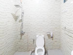 a bathroom with a shower and a white toilet at Gatsu Resort RedPartner at Karangploso in Karangploso