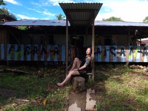 a woman sitting on a bench in front of a building at Cabaña La Paisana in Buenaventura