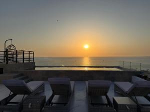 a sunset over the ocean with chairs and a pool at Modern 2BR Ocean view - Walk to Beach and Downtown in Puerto Vallarta