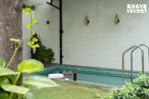 a swimming pool with wine glasses and wine bottles at StayVista at House of Palm with Bonfire & Pool in Jaipur