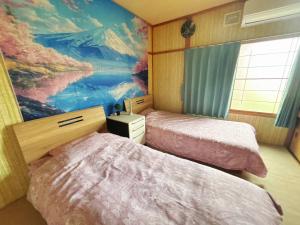 a bedroom with two beds and a painting on the wall at kitagunihouse noboribetsu in Noboribetsu