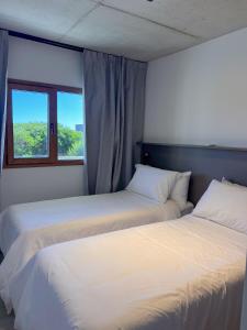 two beds in a room with a window at Jade Residencias de Mar in Villa Gesell