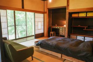 a bedroom with a bed and a desk and window at 0site house in Hokuto