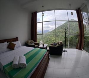 a bedroom with a bed and a large window at Villa Rivora in Kitulgala