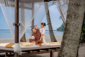 two women sitting on a table on the beach at High Season Pool Villa & Spa in Ko Kood