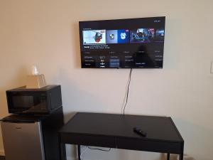 a microwave and a table with a tv on the wall at Leisure Lodge Motel in Grants