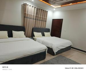 a bedroom with two beds and a window at Alpine Islamabad in Islamabad