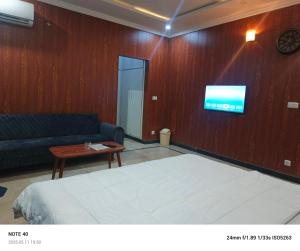 a bedroom with a bed and a couch and a tv at The Guest House Islamabad in Islamabad