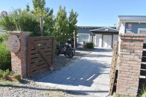 a wooden gate with a brick fence and a sidewalk at Hotel Cabañas Aparts Tierra de Glaciares in El Calafate