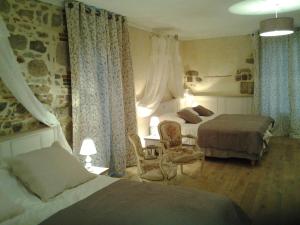 a hotel room with two beds and a chair at Le Manoir "Aux Douves" in Bazoges-en-Paillers