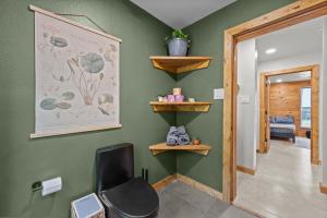 a bathroom with green walls and a black chair at LostForest Cabins in Richards