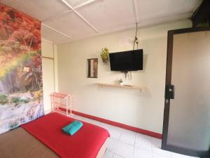 a room with a red ottoman and a flat screen tv at Ki Agung Prestise Hotel in Yogyakarta