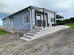 a blue house with stairs leading to a porch at The Blue Bach in Opunake