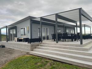 a house with a large deck with a table and chairs at The Blue Bach in Opunake