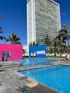 a swimming pool in front of a tall building at Casa de playa, a pasos del mar in Mazatlán