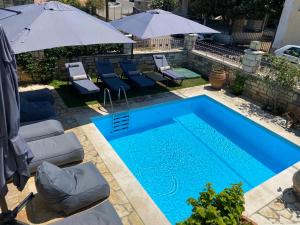 a swimming pool with chairs and umbrellas next to it at Petrino Serene Studios in Kakovatos