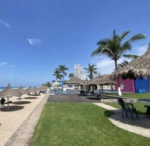a group of tables and straw umbrellas on a beach at Casa de playa, a pasos del mar in Mazatlán