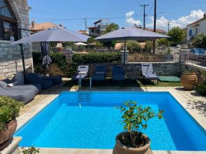 a blue swimming pool with chairs and umbrellas at Petrino Serene Studios in Kakovatos