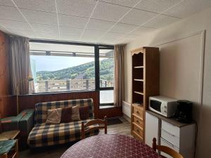 un salon avec un canapé et une grande fenêtre dans l'établissement Appartement 2 pièces vue montagne, proche pistes et lac - FR-1-814-64, à Besse-et-Saint-Anastaise